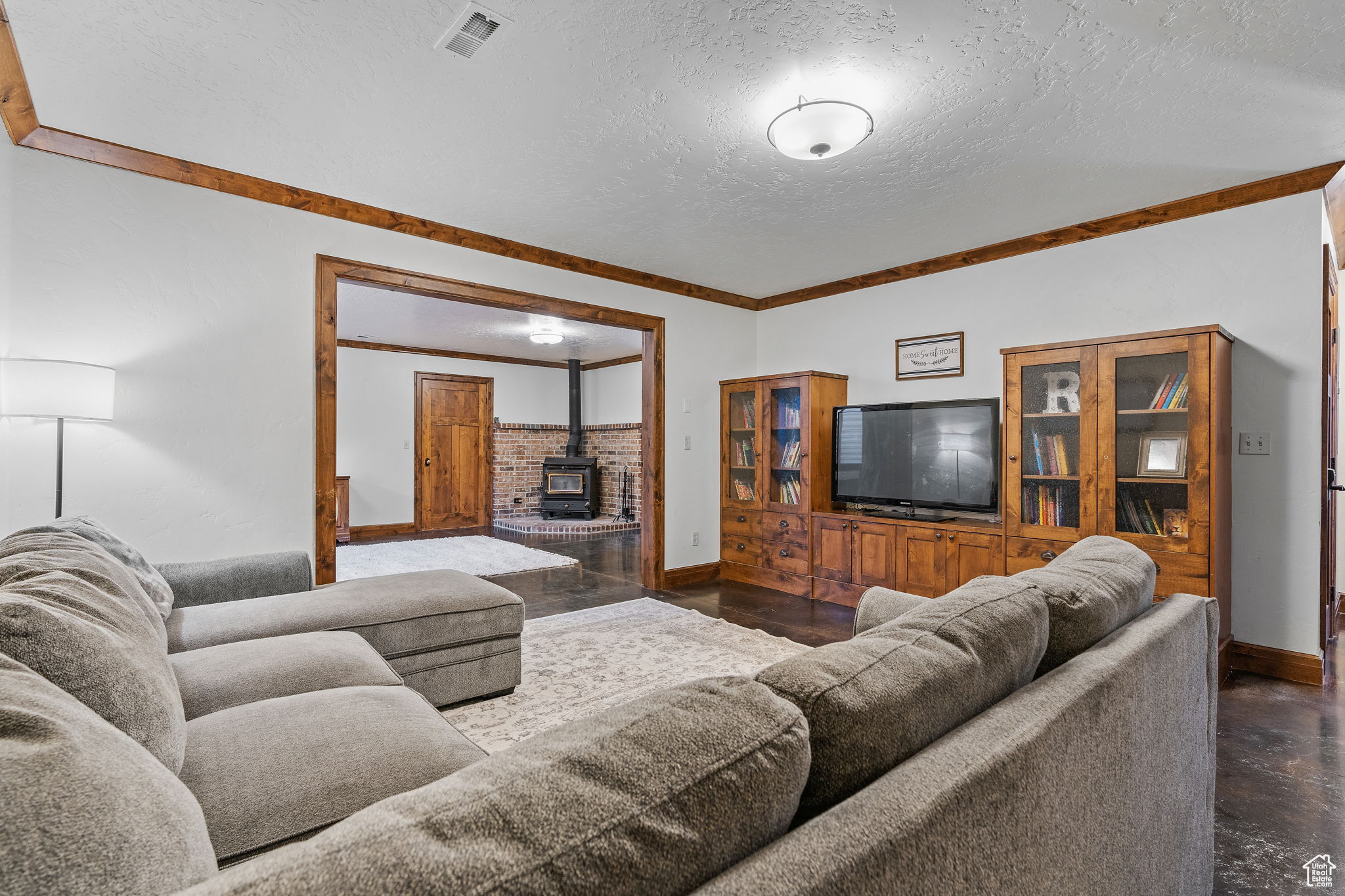 Living room with crown molding, a wood stove, and a textured ceiling