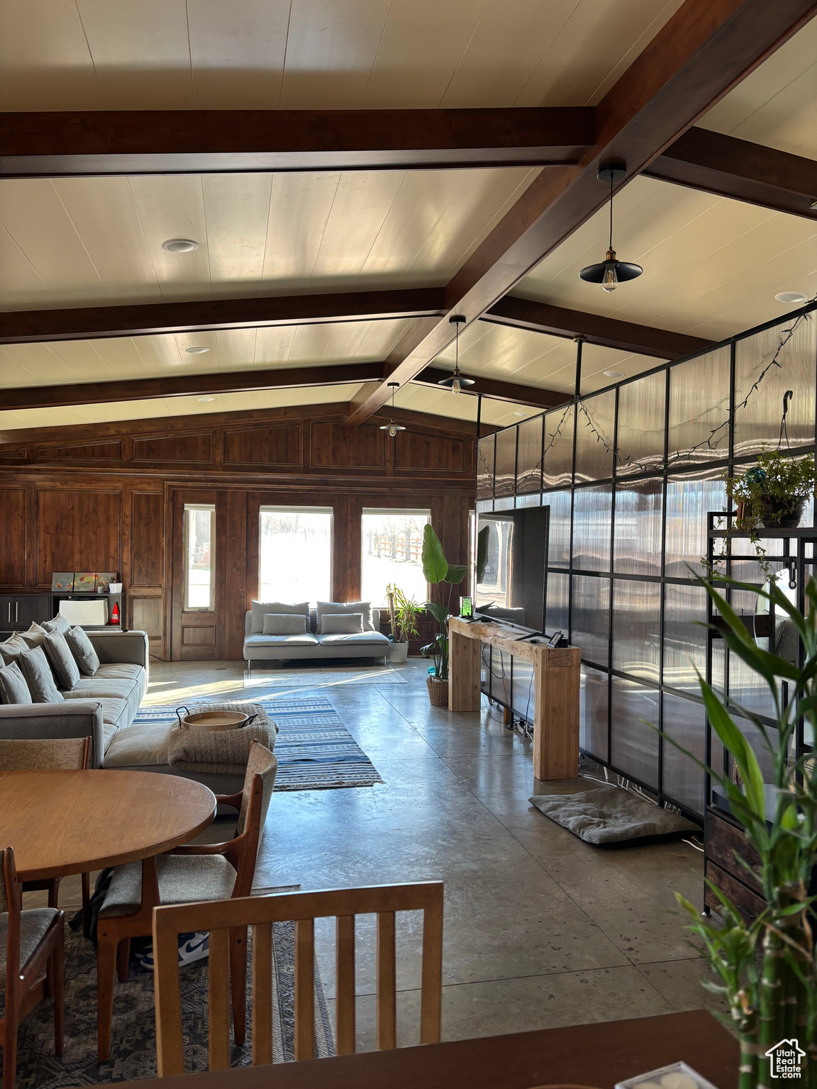 Living room featuring vaulted ceiling with beams and wooden walls