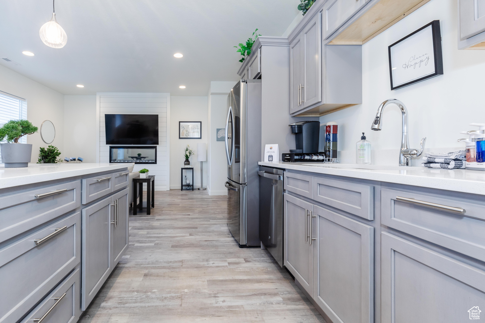 Kitchen with decorative light fixtures, gray cabinets, light hardwood / wood-style floors, and appliances with stainless steel finishes
