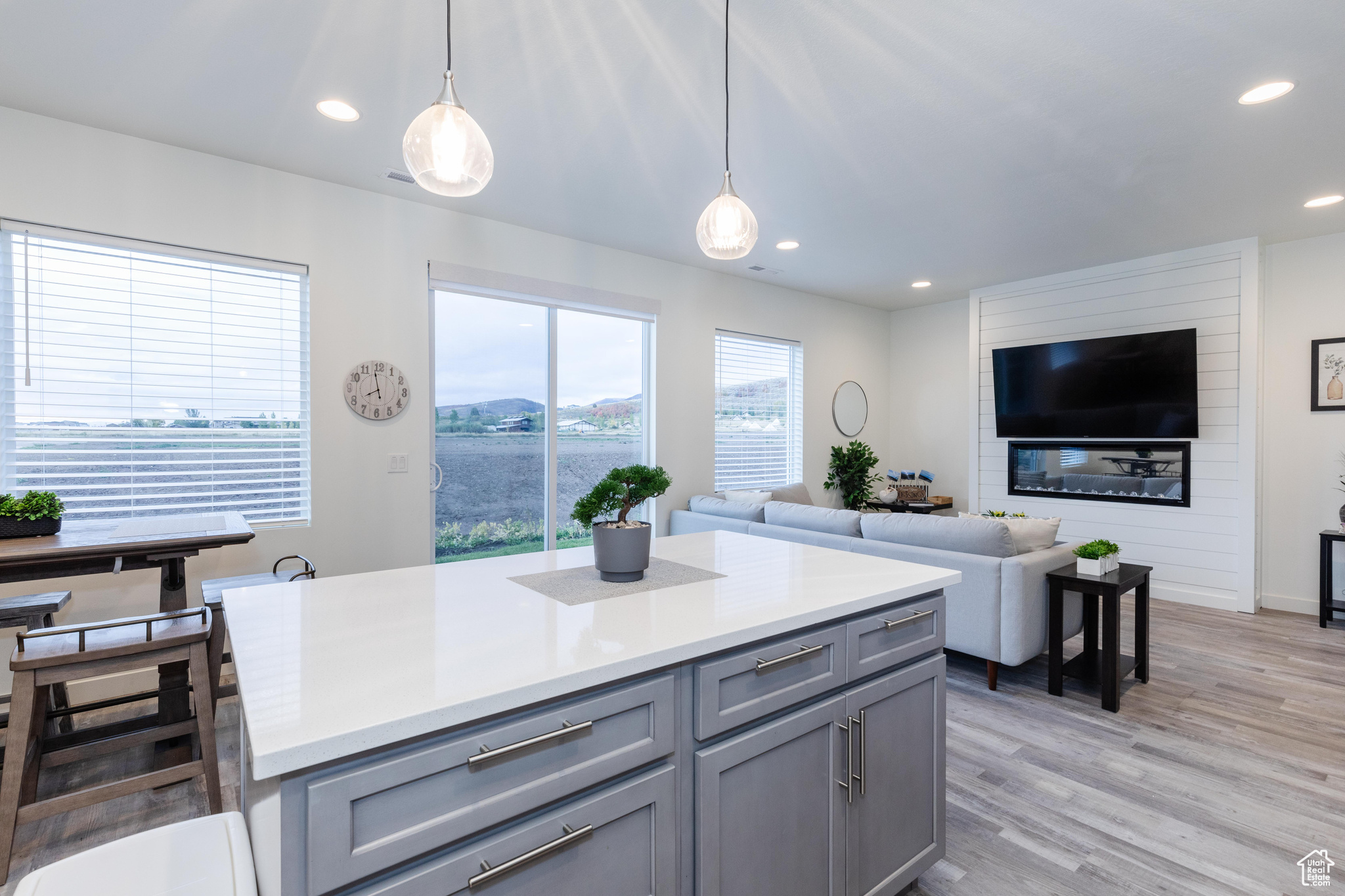 Kitchen featuring light wood-type flooring, hanging light fixtures, and gray cabinetry
