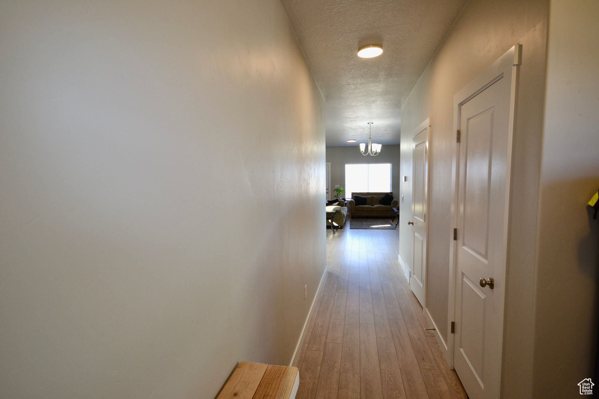 Corridor with wood-type flooring, a chandelier, and a textured ceiling