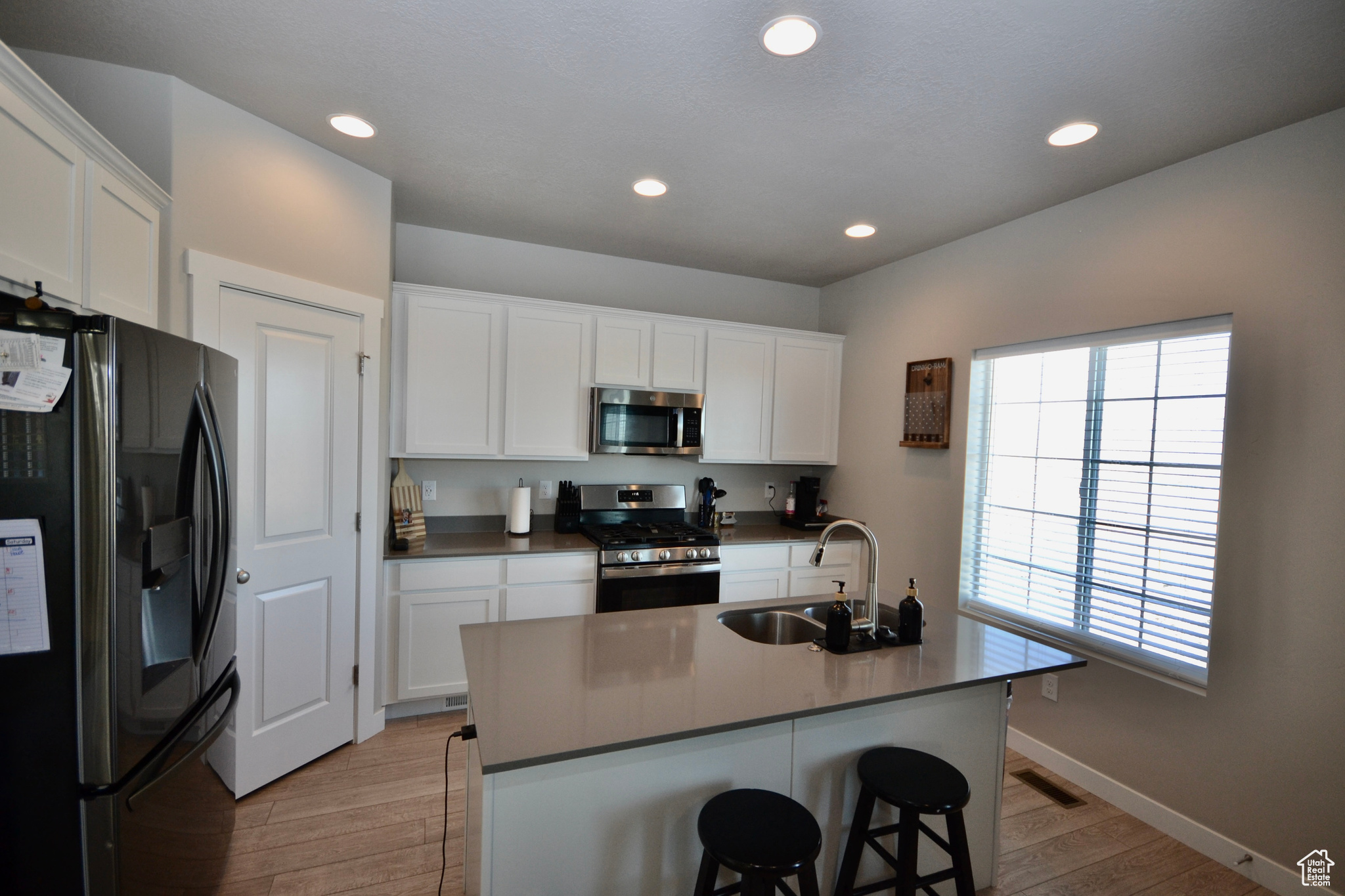 Kitchen with white cabinetry, stainless steel appliances, sink, and a center island with sink