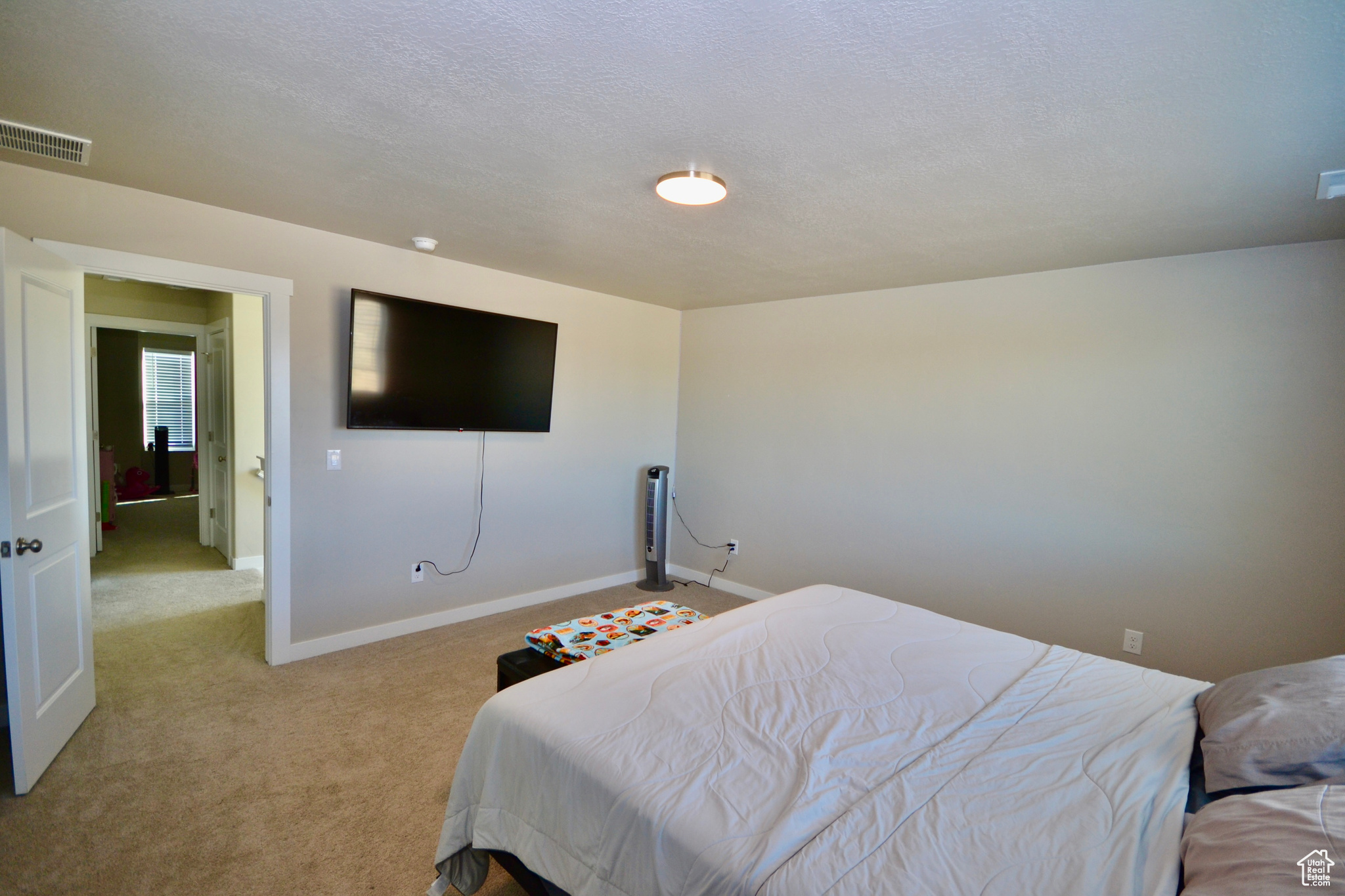 Bedroom with light colored carpet and a textured ceiling