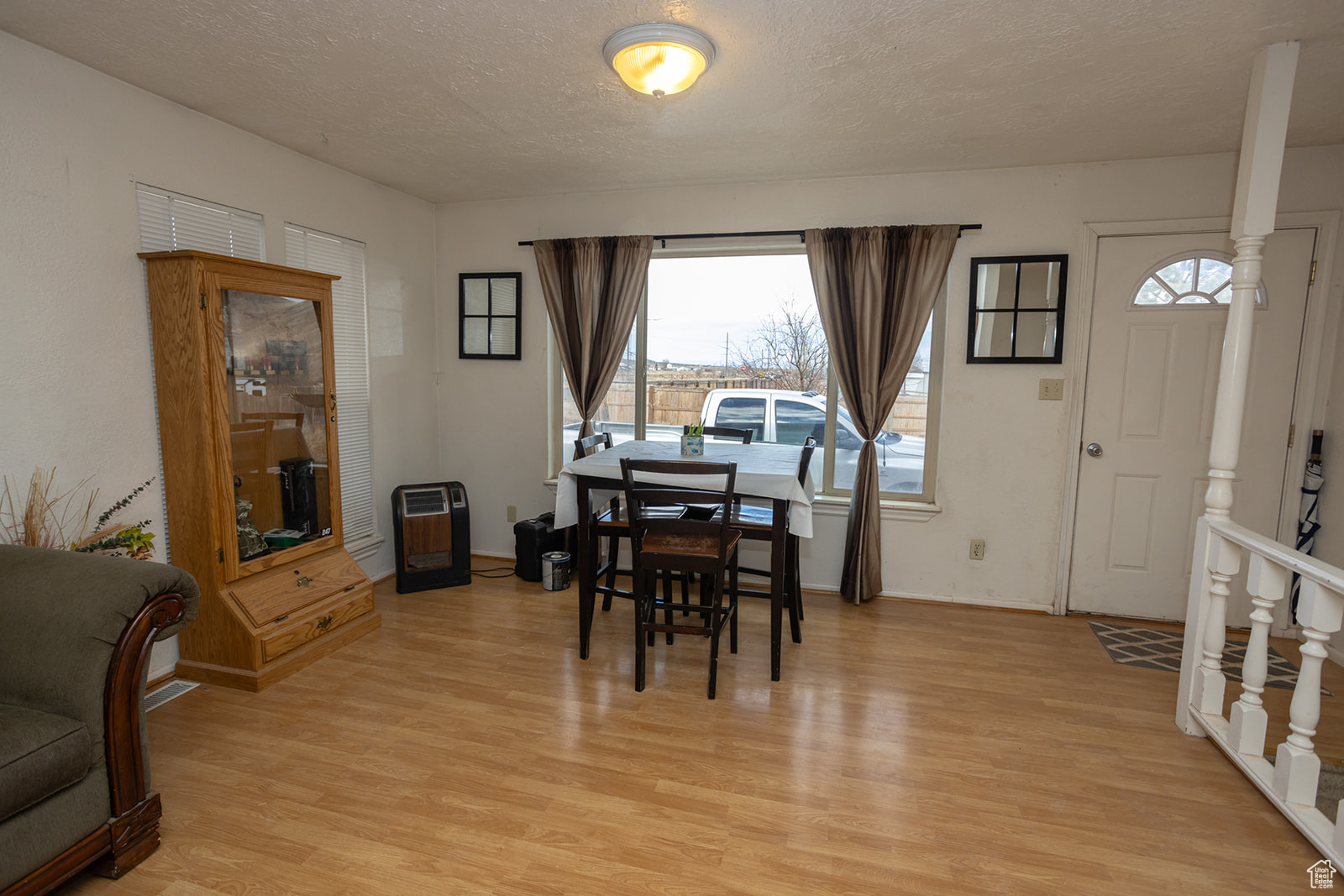 Dining area featuring heating unit, light hardwood / wood-style floors, and a textured ceiling
