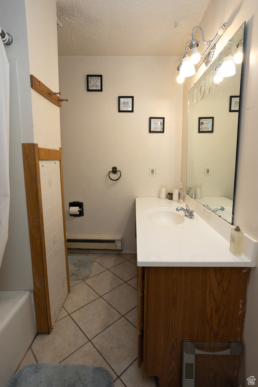 Bathroom featuring a baseboard heating unit, vanity, a textured ceiling, a tub to relax in, and tile patterned floors