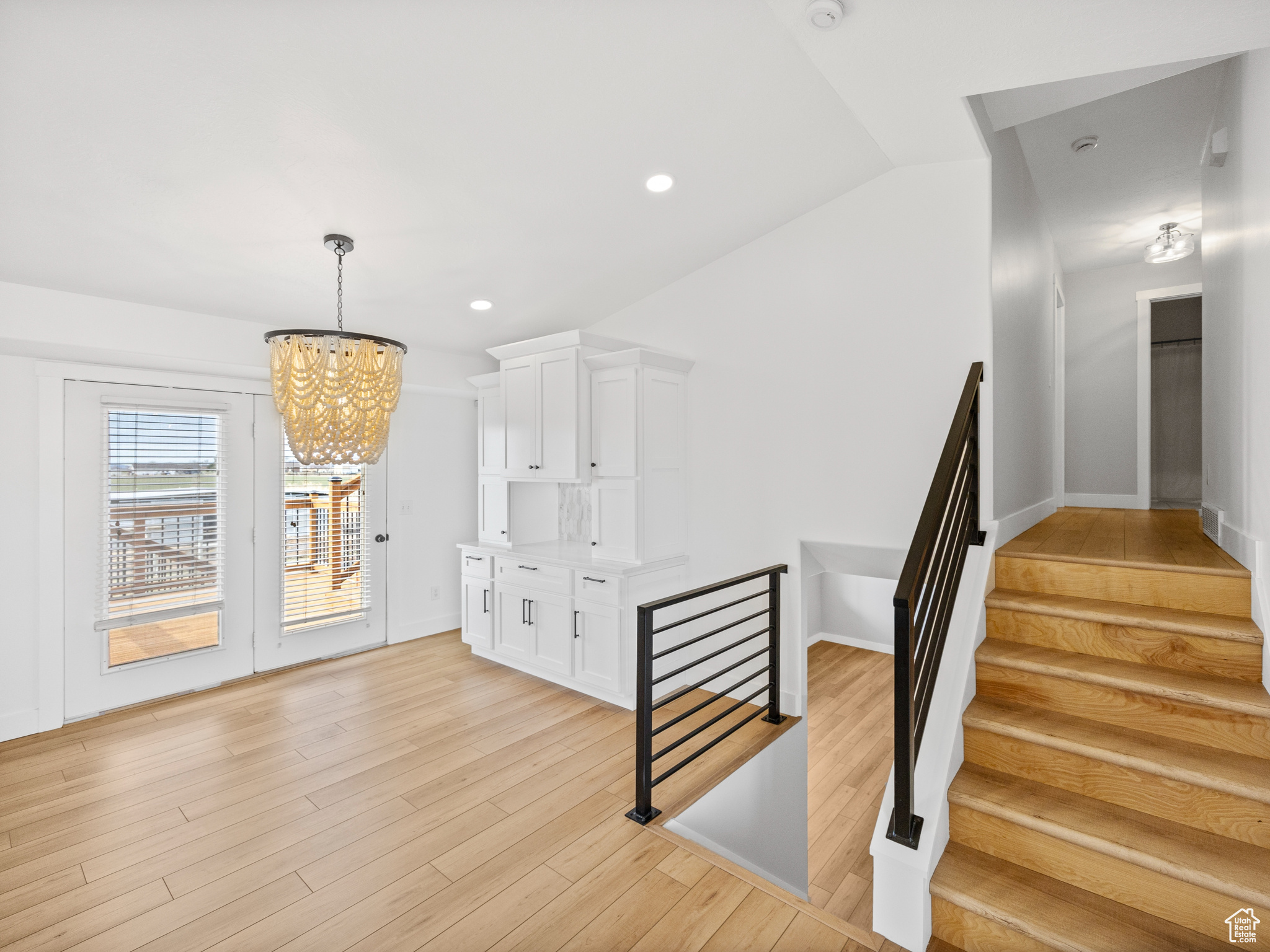 Staircase with wood-type flooring, vaulted ceiling, and a notable chandelier