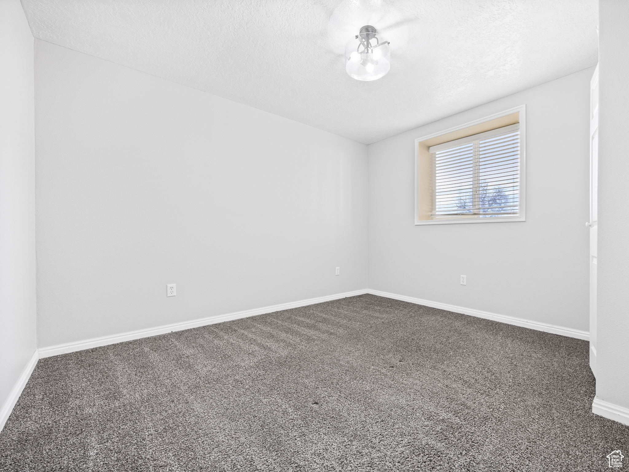Carpeted spare room with a textured ceiling