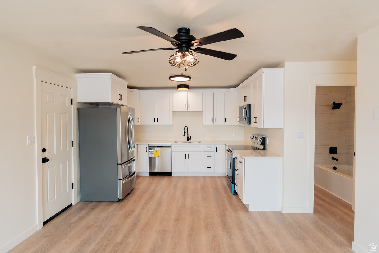 Kitchen featuring sink, light wood-type flooring, white cabinets, and appliances with stainless steel finishes
