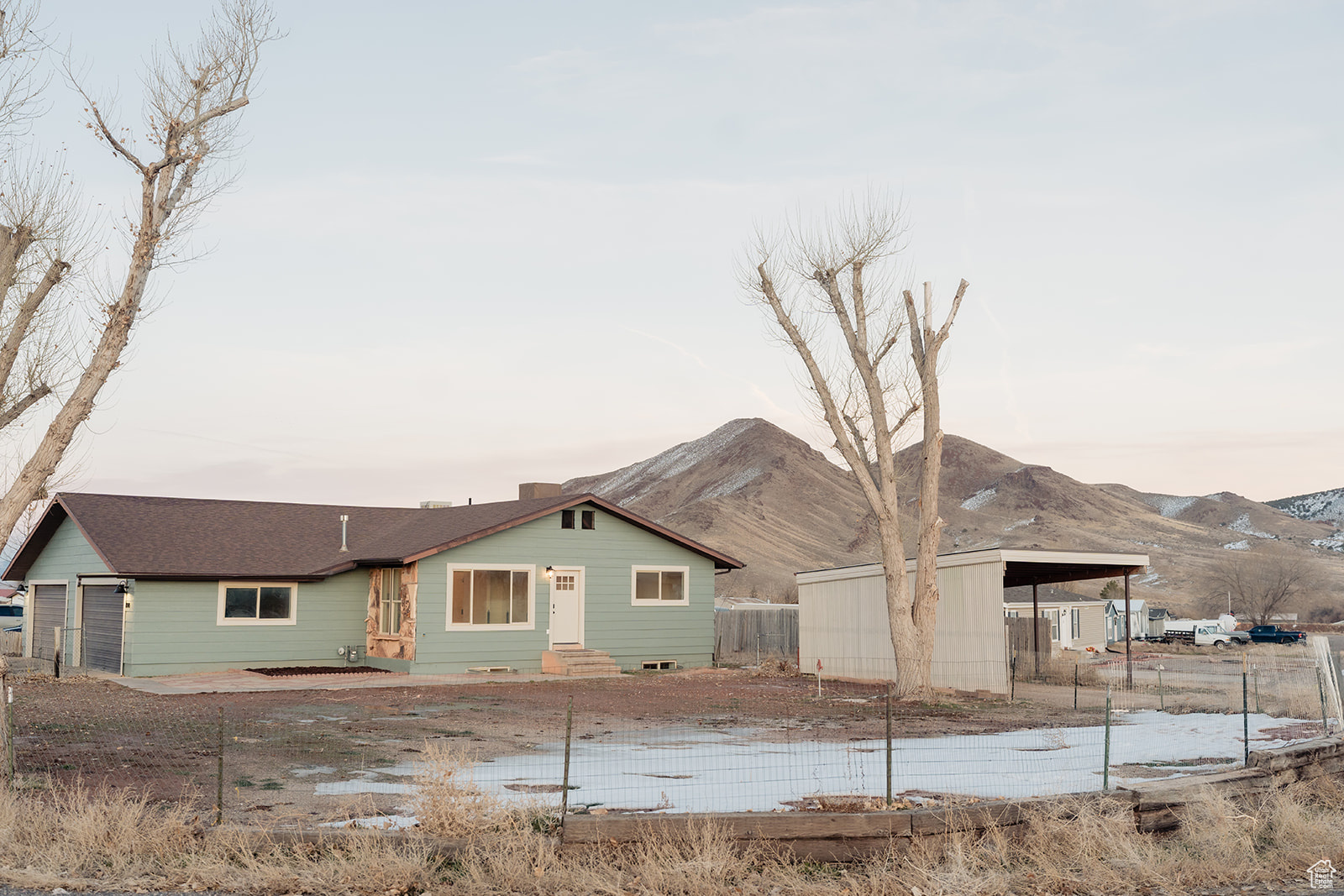 Back house at dusk with a carport, a mountain view, and a garage