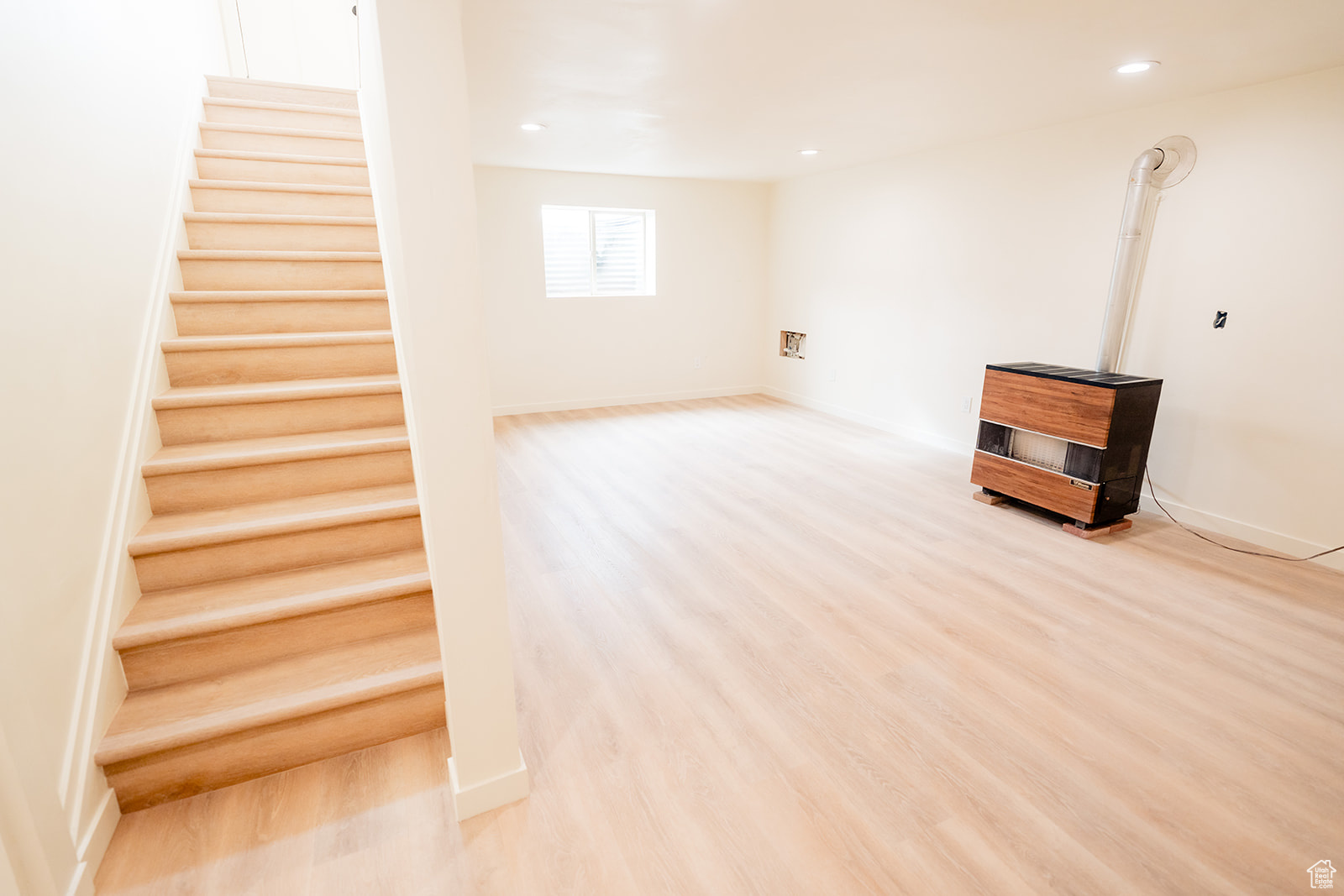 Basement featuring light hardwood / wood-style floors and a wood stove