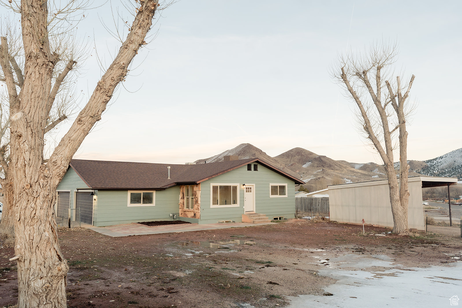 Back house at dusk featuring a garage and a mountain view