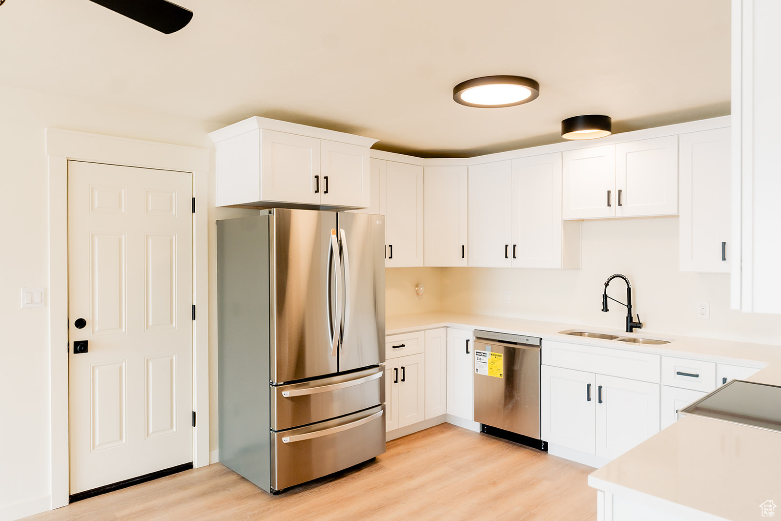 Kitchen featuring stainless steel appliances, light hardwood / wood-style floors, sink, and white cabinets