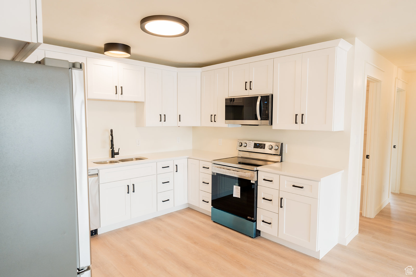 Kitchen featuring white cabinetry, appliances with stainless steel finishes, sink, and light hardwood / wood-style floors
