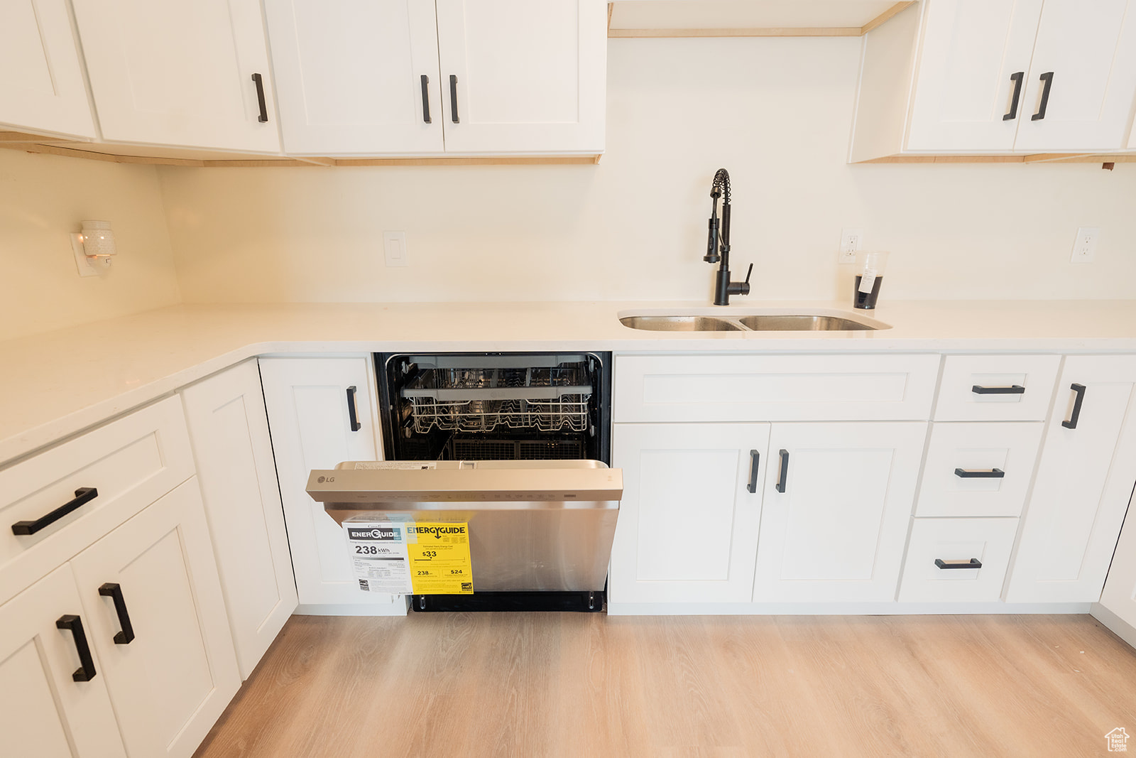 Kitchen featuring sink, light hardwood / wood-style flooring, dishwasher, and white cabinets
