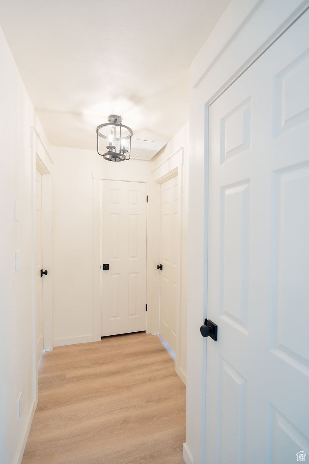 Hall with a notable chandelier and light hardwood / wood-style flooring