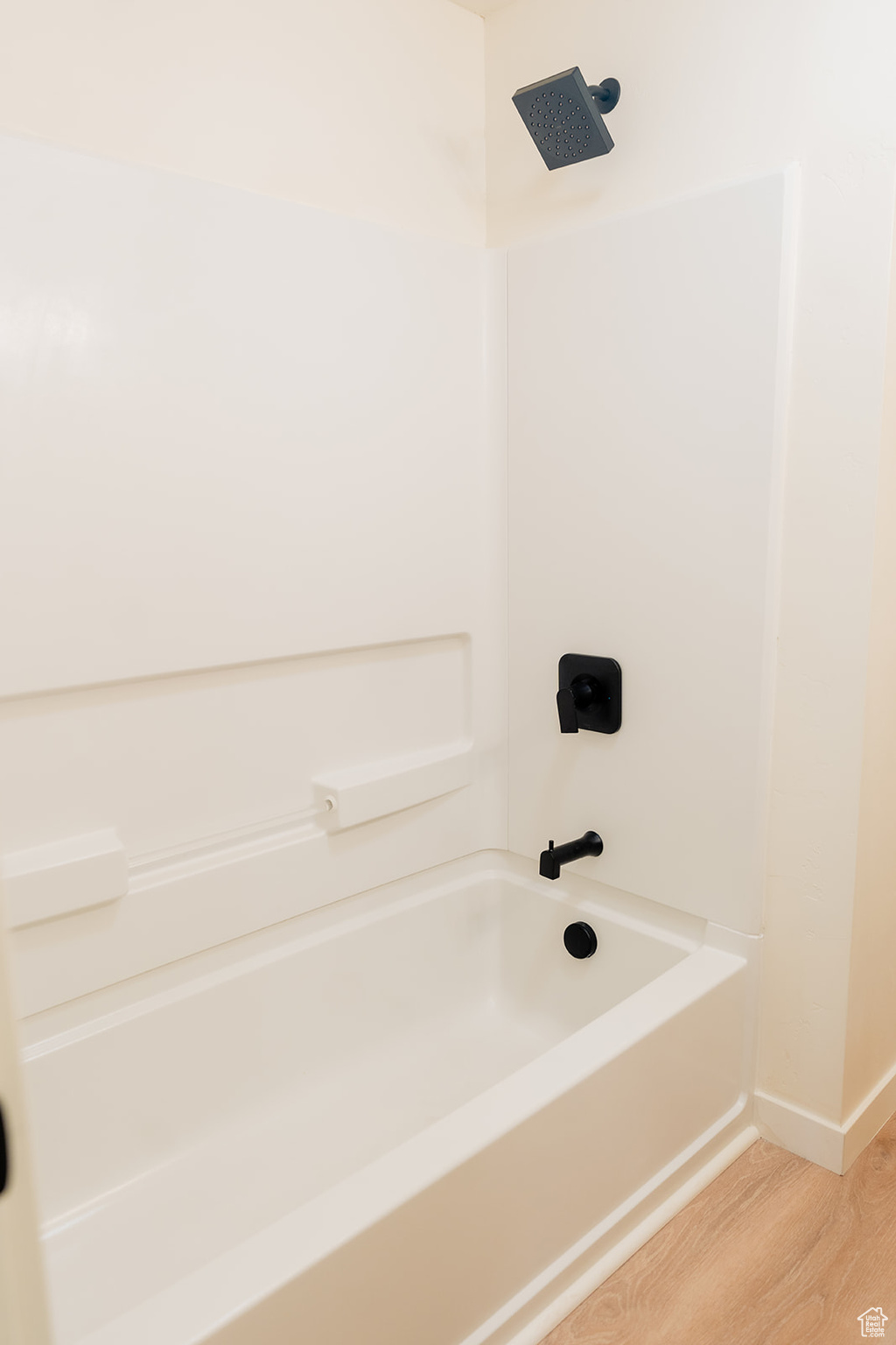 Bathroom featuring hardwood / wood-style flooring and washtub / shower combination