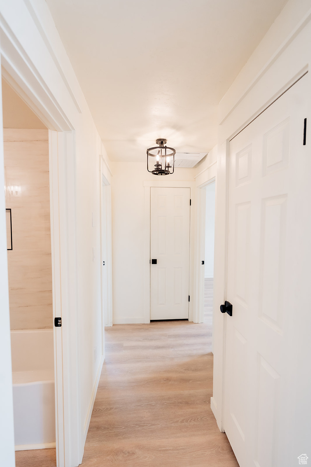 Hall with light hardwood / wood-style flooring and a chandelier