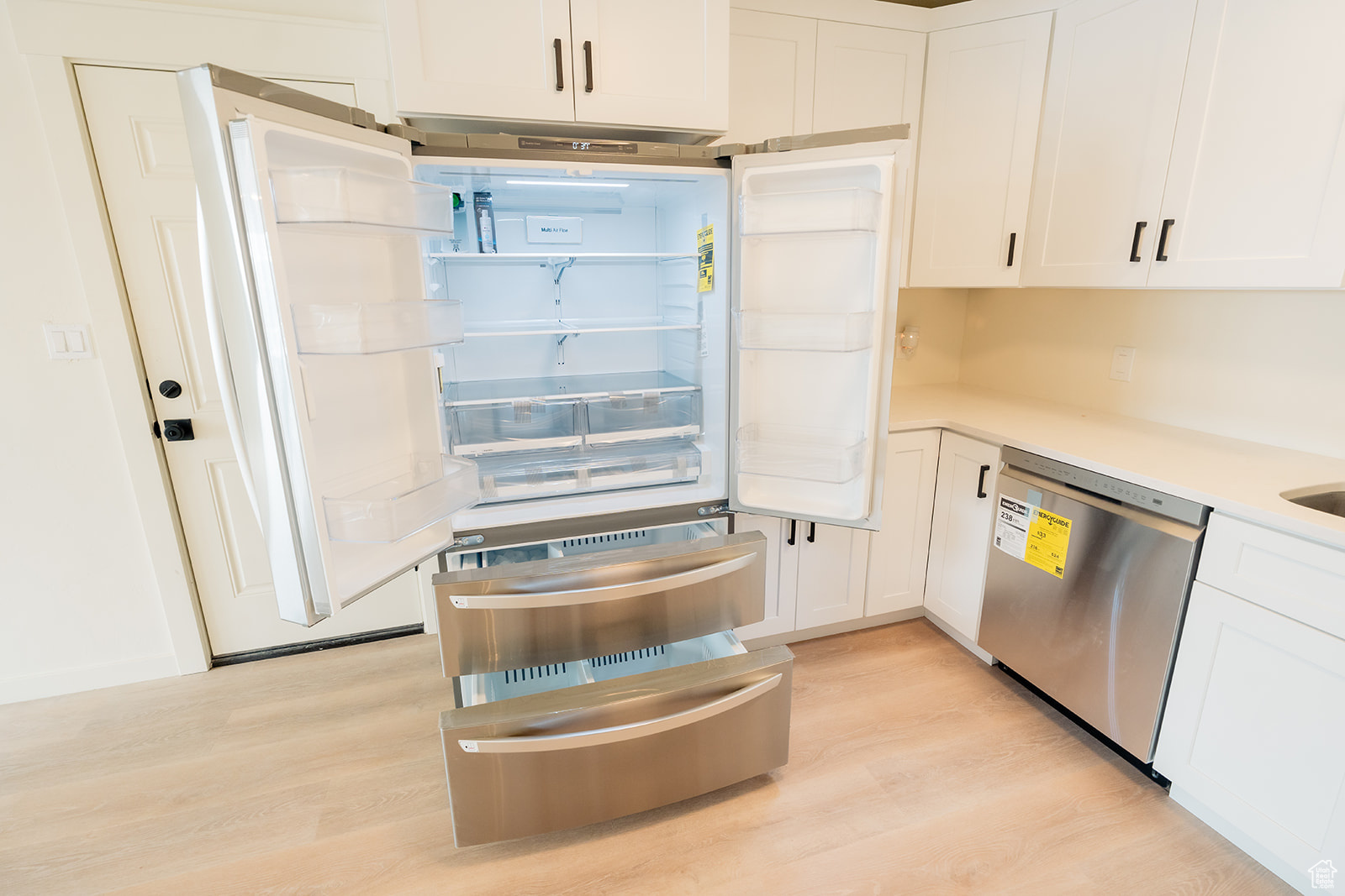 Kitchen with white cabinets, light hardwood / wood-style floors, and dishwasher