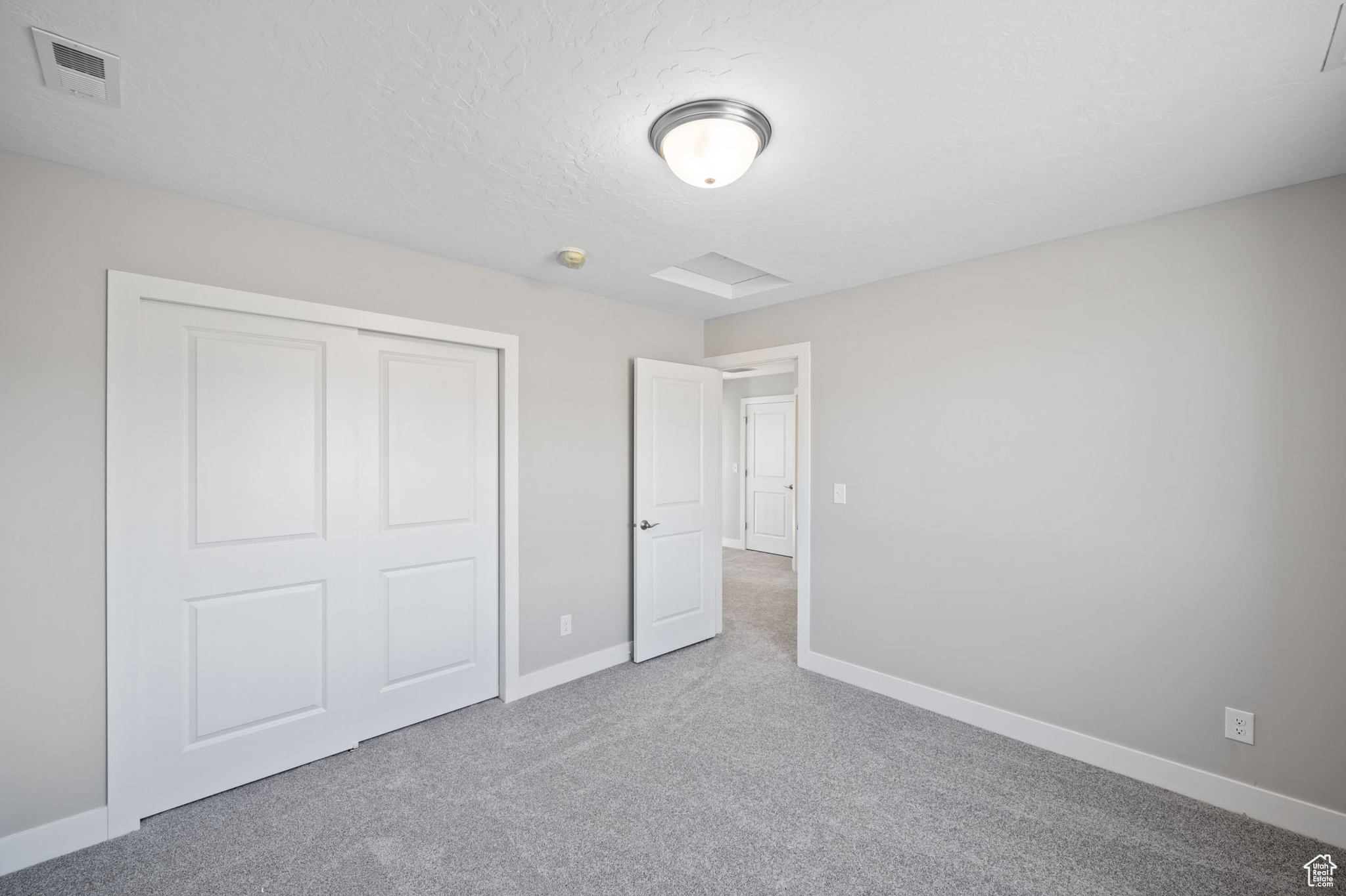 Unfurnished bedroom featuring a closet, a textured ceiling, and carpet flooring