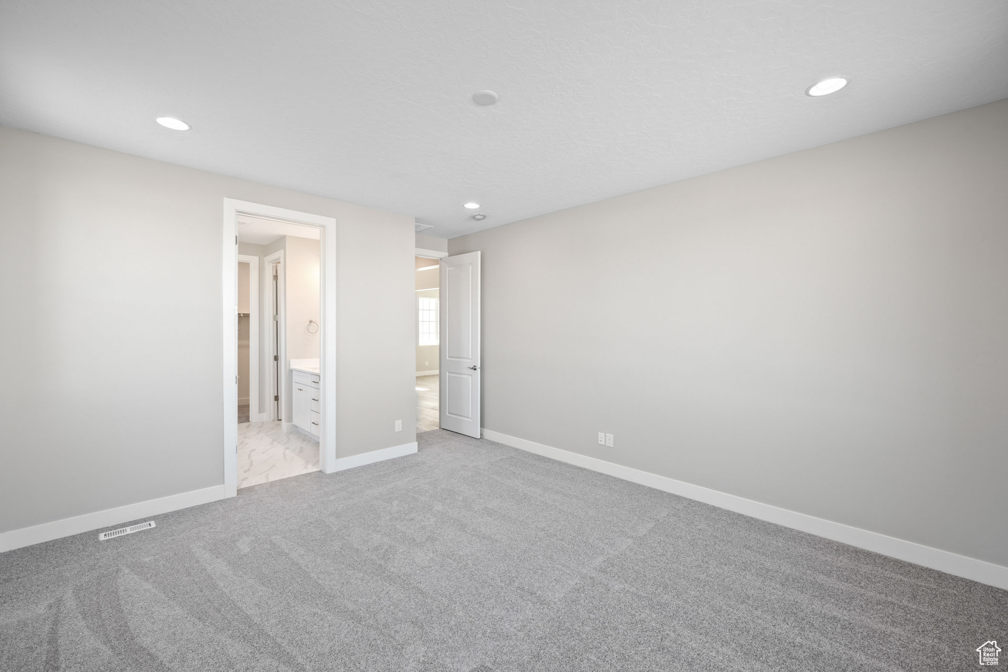Unfurnished bedroom featuring light colored carpet and ensuite bathroom