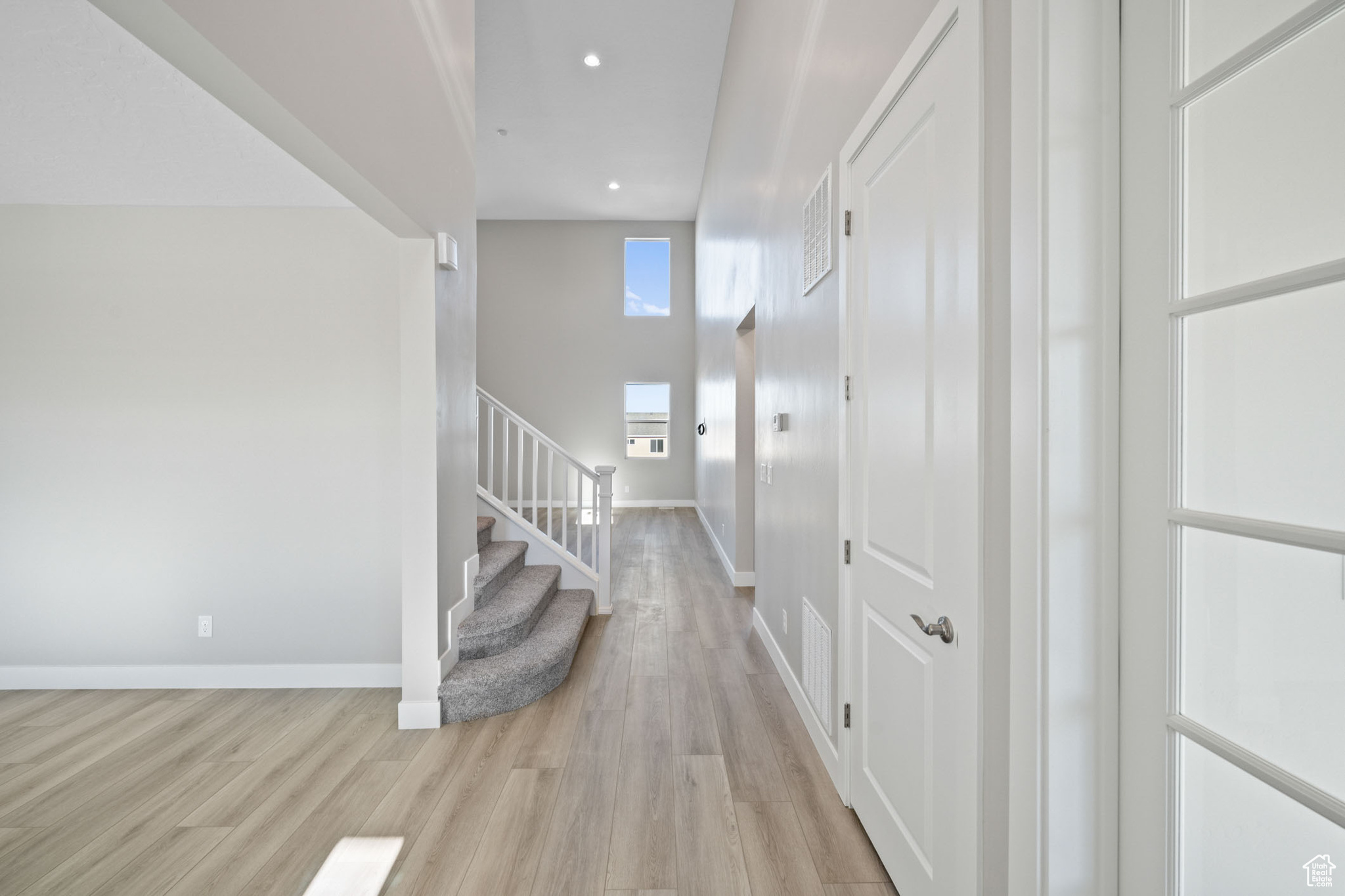 Hallway with light hardwood / wood-style flooring and a high ceiling