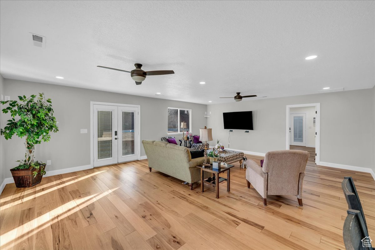 Living room with french doors, ceiling fan, and light hardwood / wood-style flooring