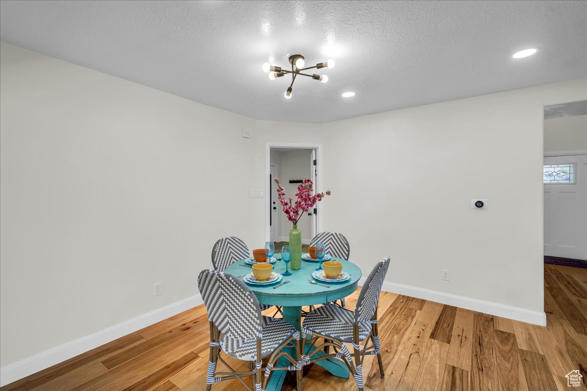 Dining space featuring an inviting chandelier, wood-type flooring, and a textured ceiling