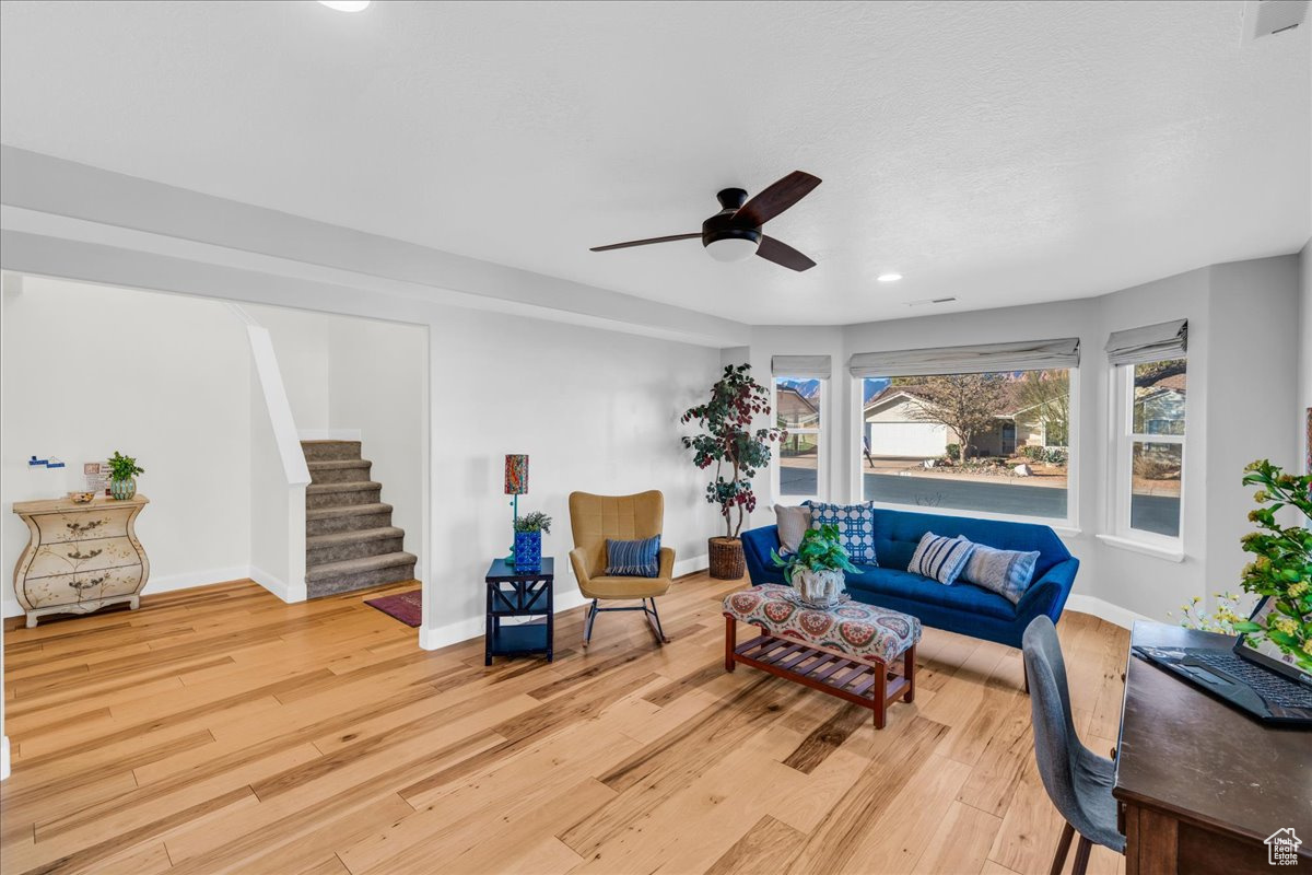 Living room with ceiling fan and light hardwood / wood-style flooring
