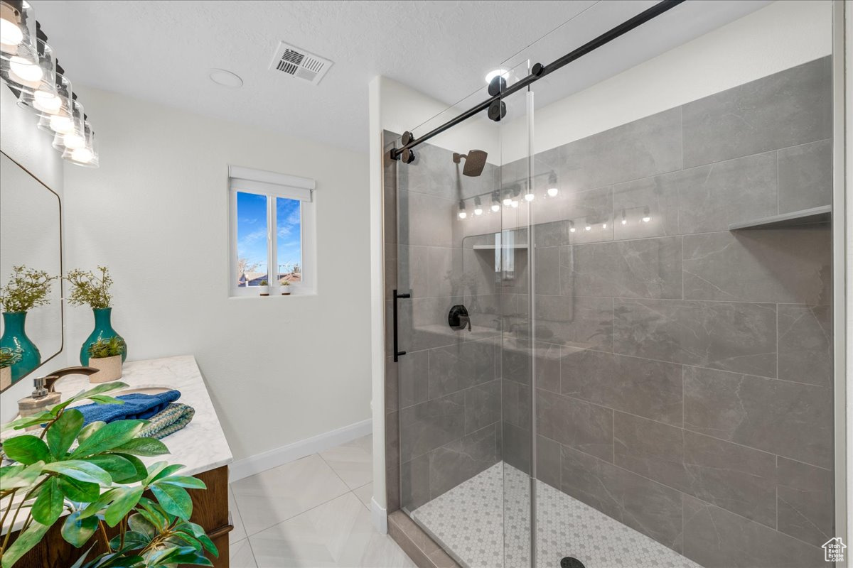 Bathroom featuring tile patterned floors, vanity, and an enclosed shower