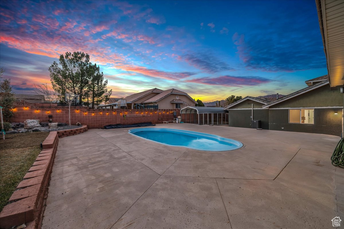 Pool at dusk featuring a patio area
