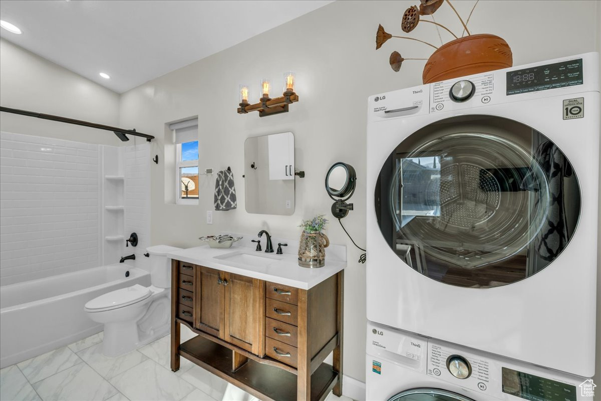 Full bathroom with vanity, stacked washer / drying machine, shower / bathtub combination, and toilet