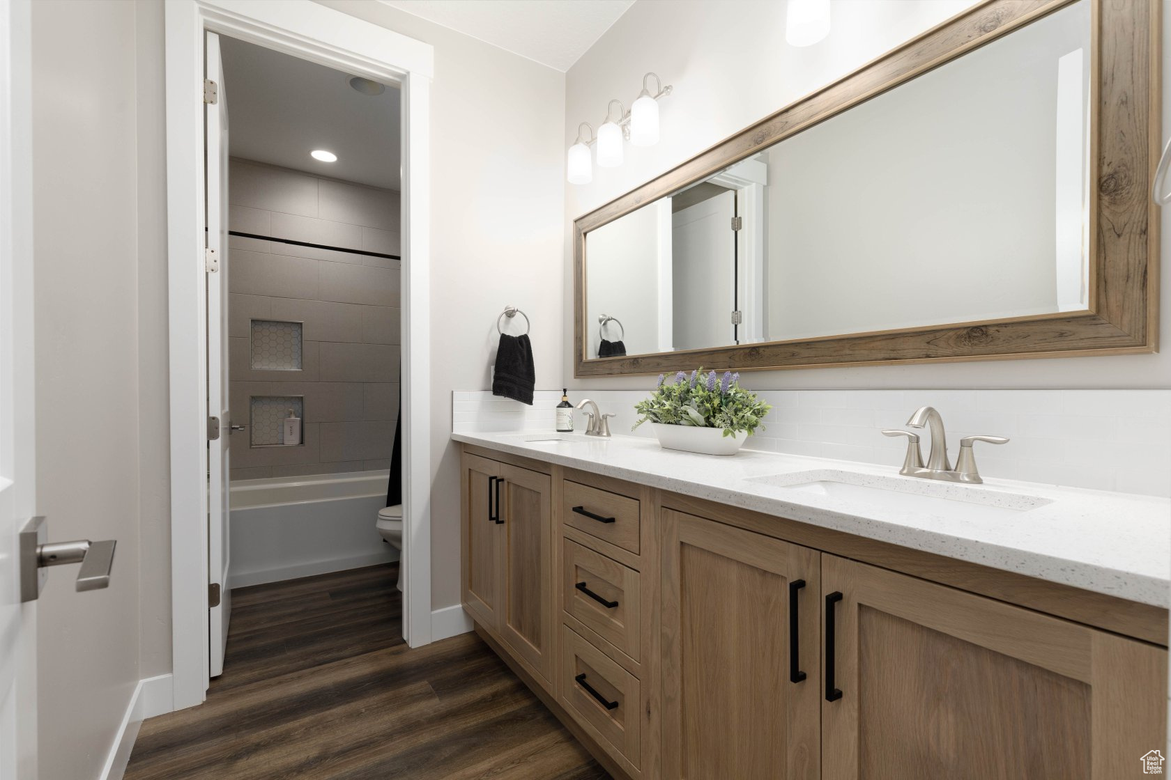 Full bathroom with vanity, hardwood / wood-style floors, tiled shower / bath combo, and toilet