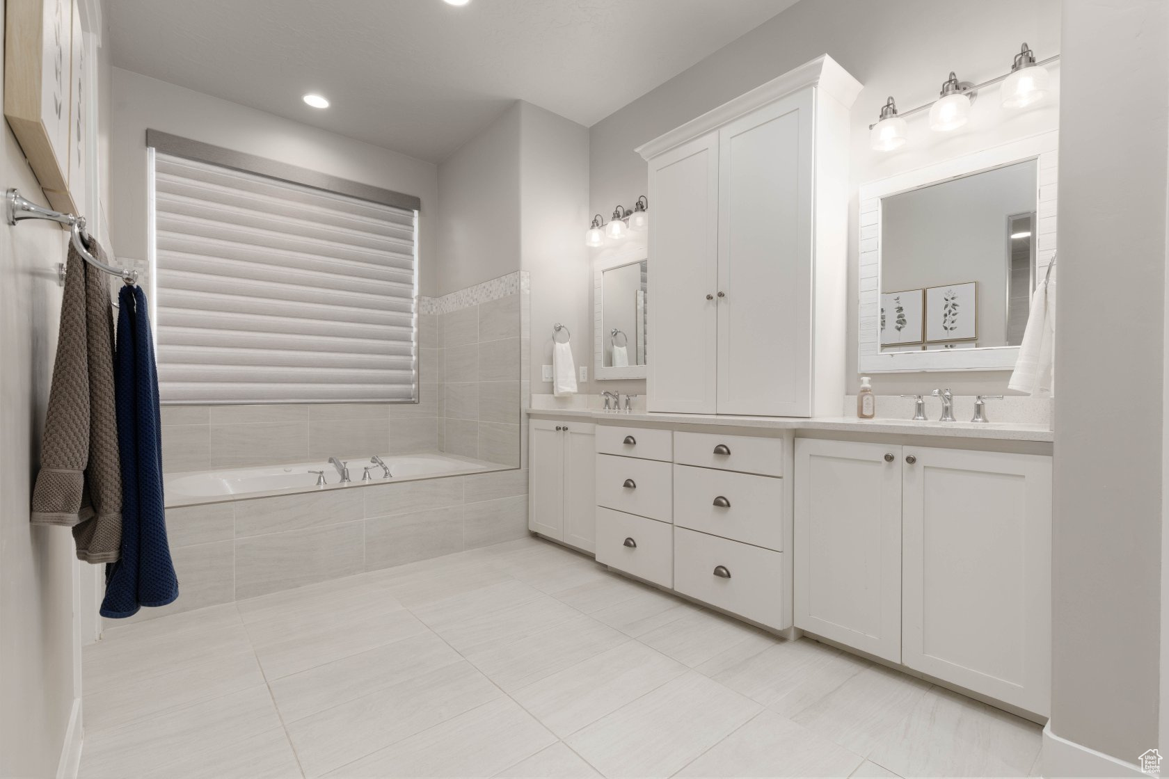 Bathroom with a relaxing tiled tub, vanity, and tile patterned floors