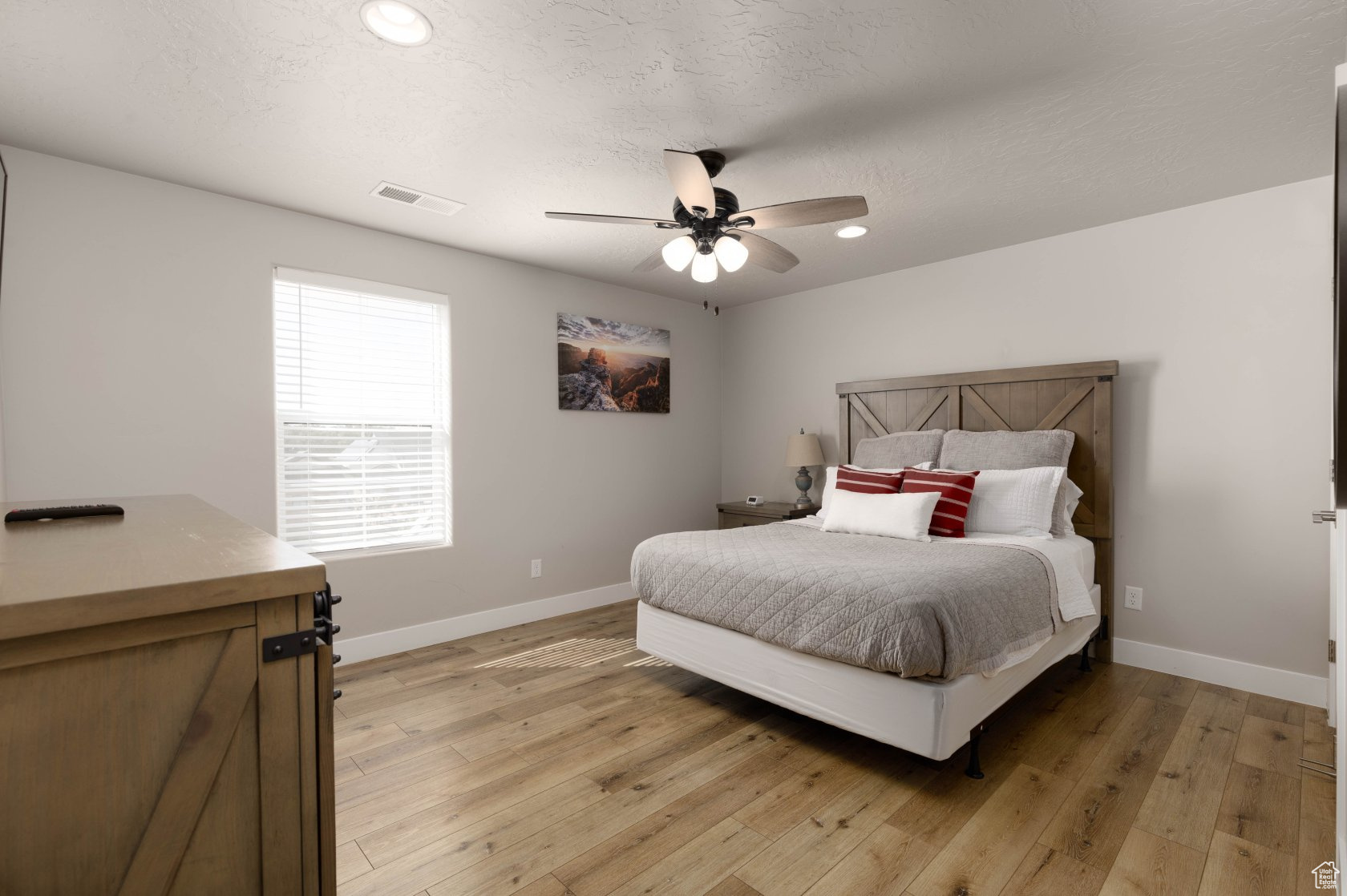Bedroom with ceiling fan, a textured ceiling, and light hardwood / wood-style flooring