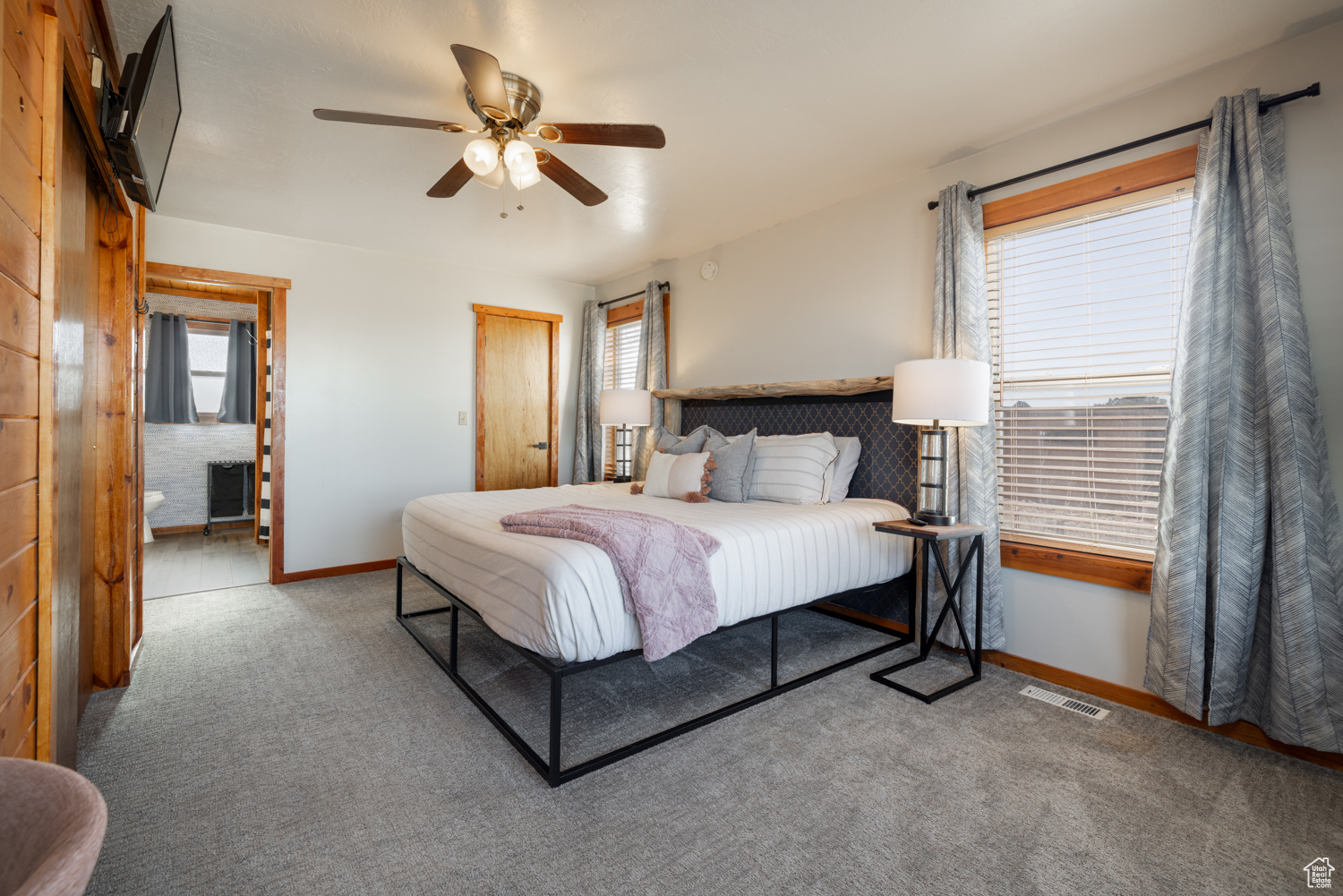 Carpeted bedroom with multiple windows and ceiling fan