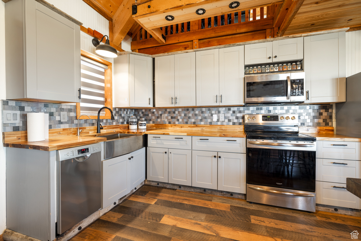 Kitchen featuring butcher block counters, sink, white cabinetry, appliances with stainless steel finishes, and backsplash