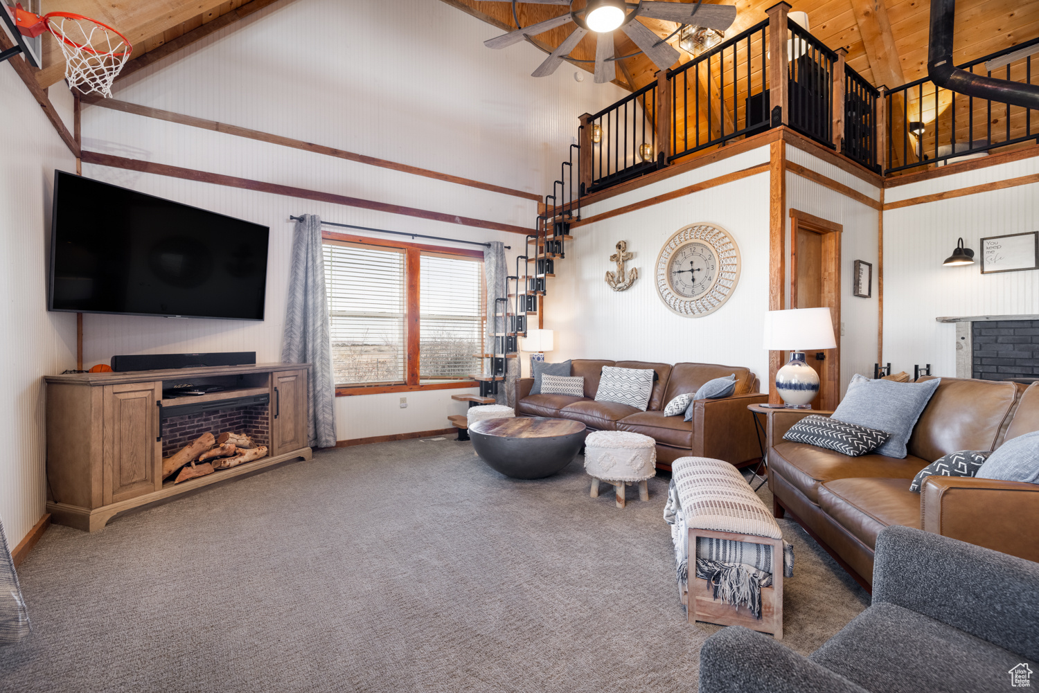 Carpeted living room with high vaulted ceiling and ceiling fan