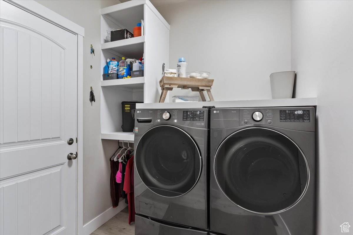 Washroom featuring light hardwood / wood-style floors and washing machine and dryer