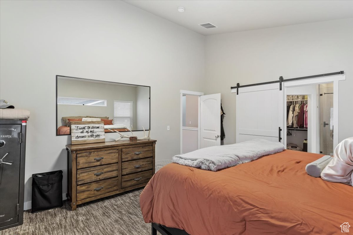 Bedroom featuring a walk in closet, carpet floors, a closet, a barn door, and a high ceiling