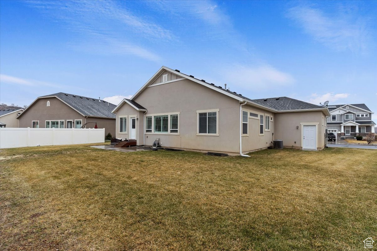 Rear view of house featuring cooling unit, a patio area, and a lawn