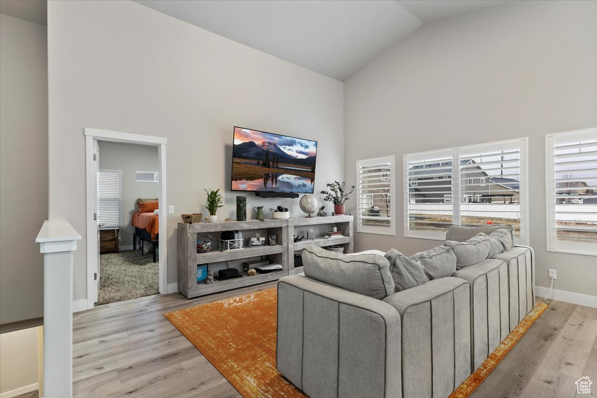 Living room with light wood-type flooring and high vaulted ceiling