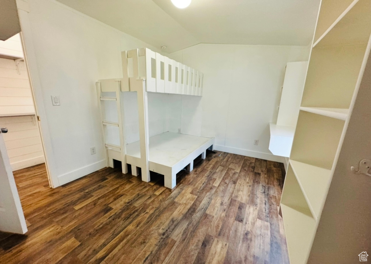 Unfurnished bedroom featuring lofted ceiling and dark hardwood / wood-style floors