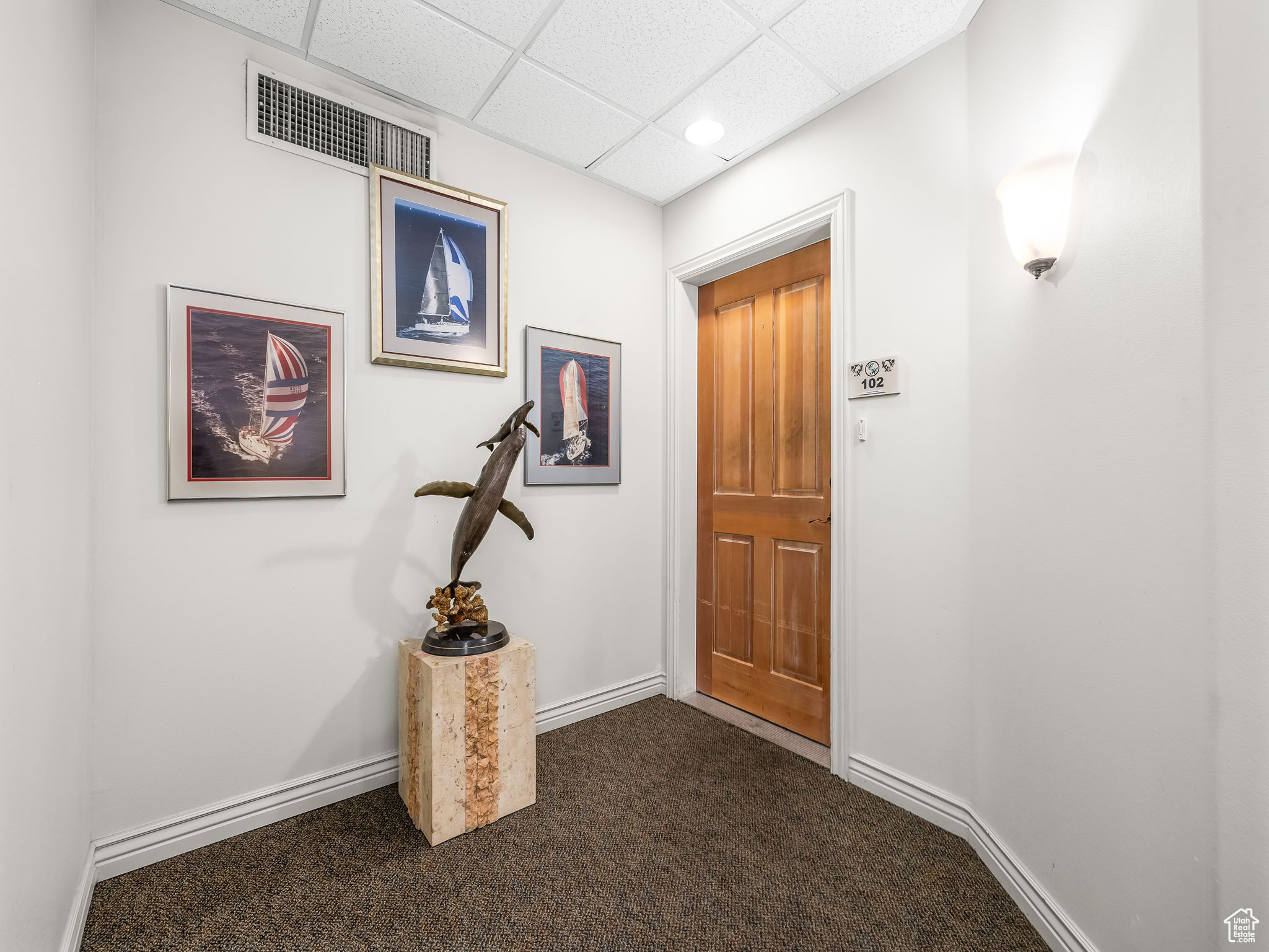 Entryway featuring dark carpet and a drop ceiling