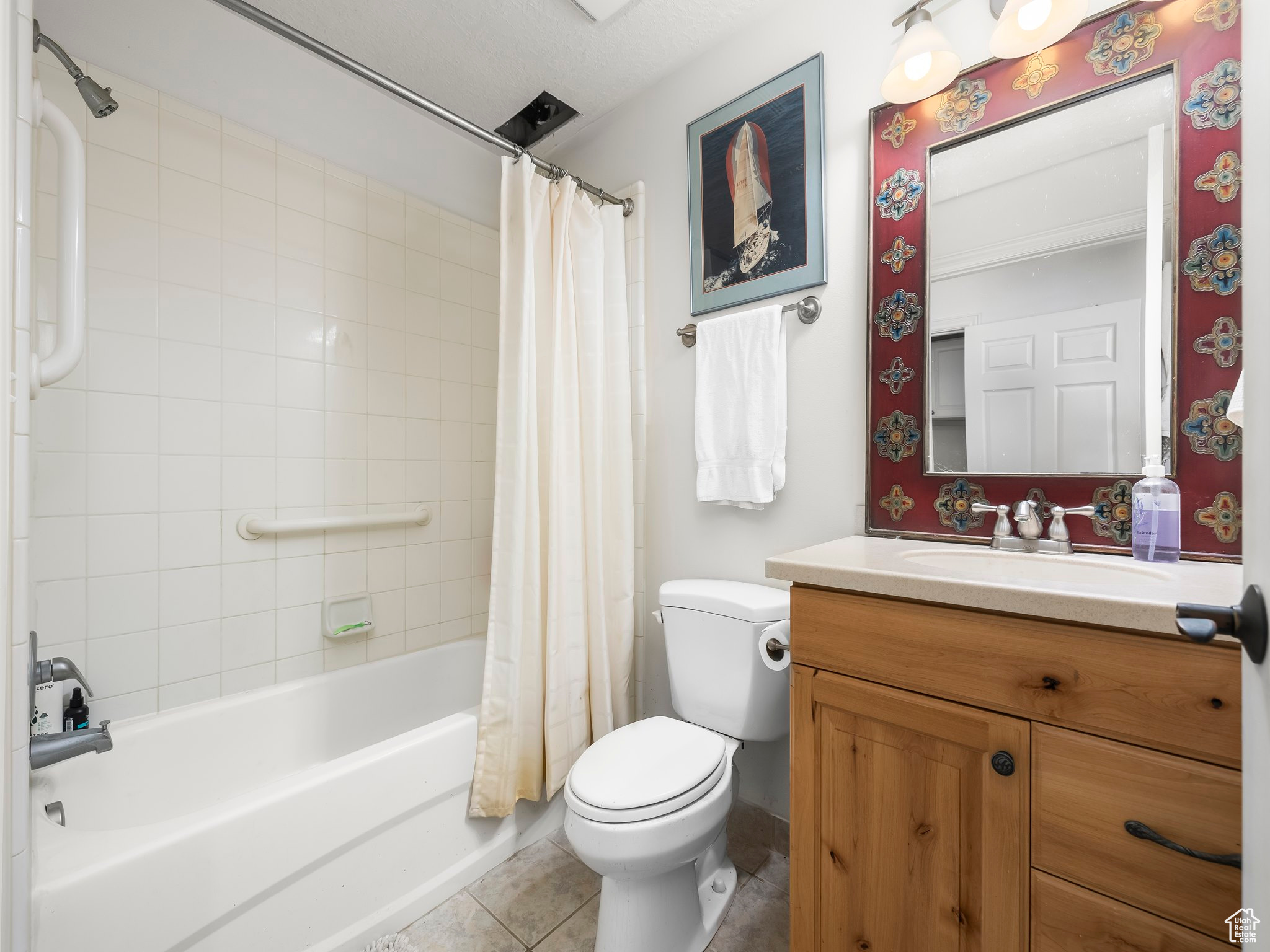 Full bathroom with tile patterned flooring, vanity, shower / tub combo, and toilet