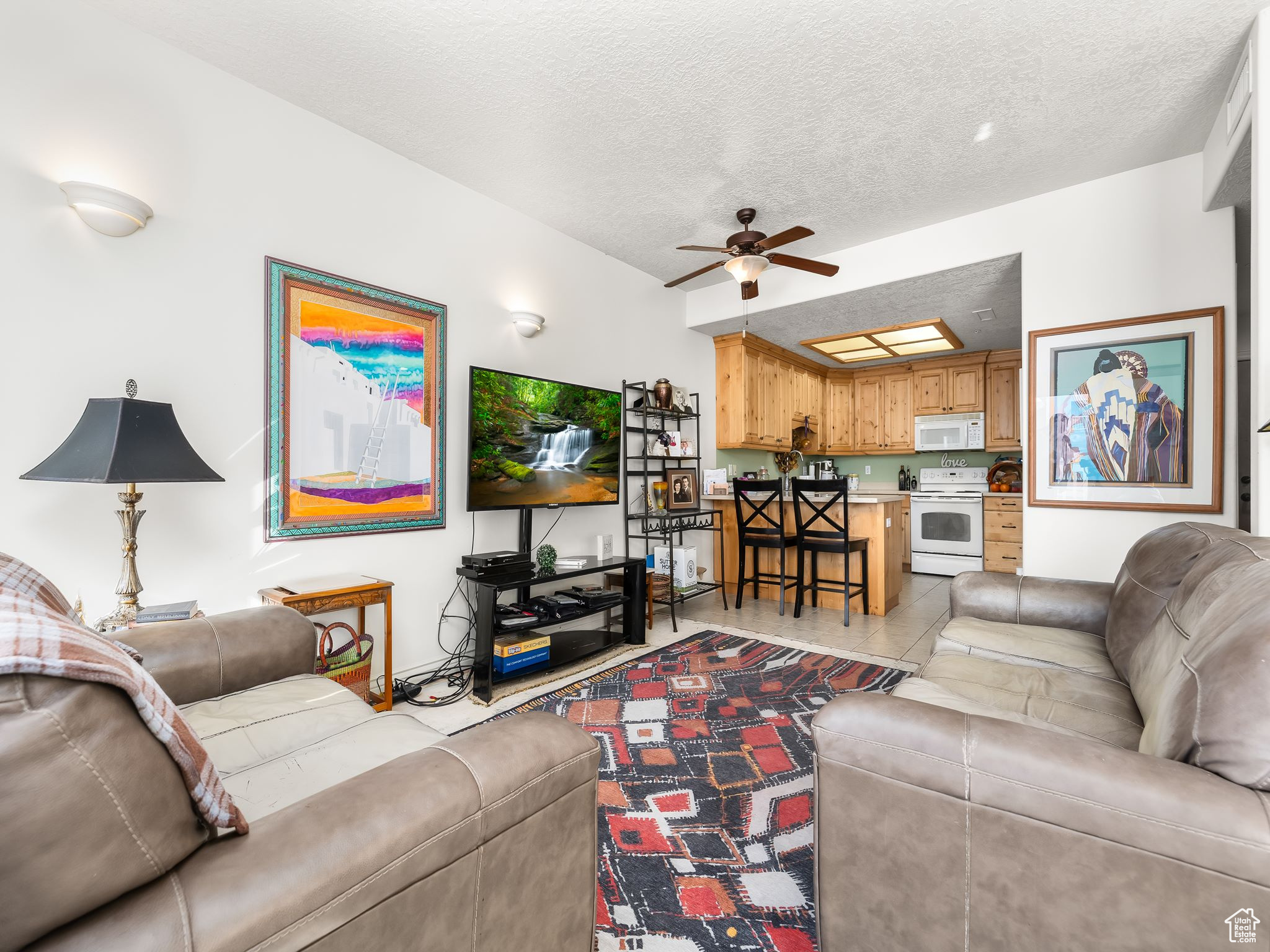 Living room with ceiling fan, a textured ceiling, and light tile patterned flooring