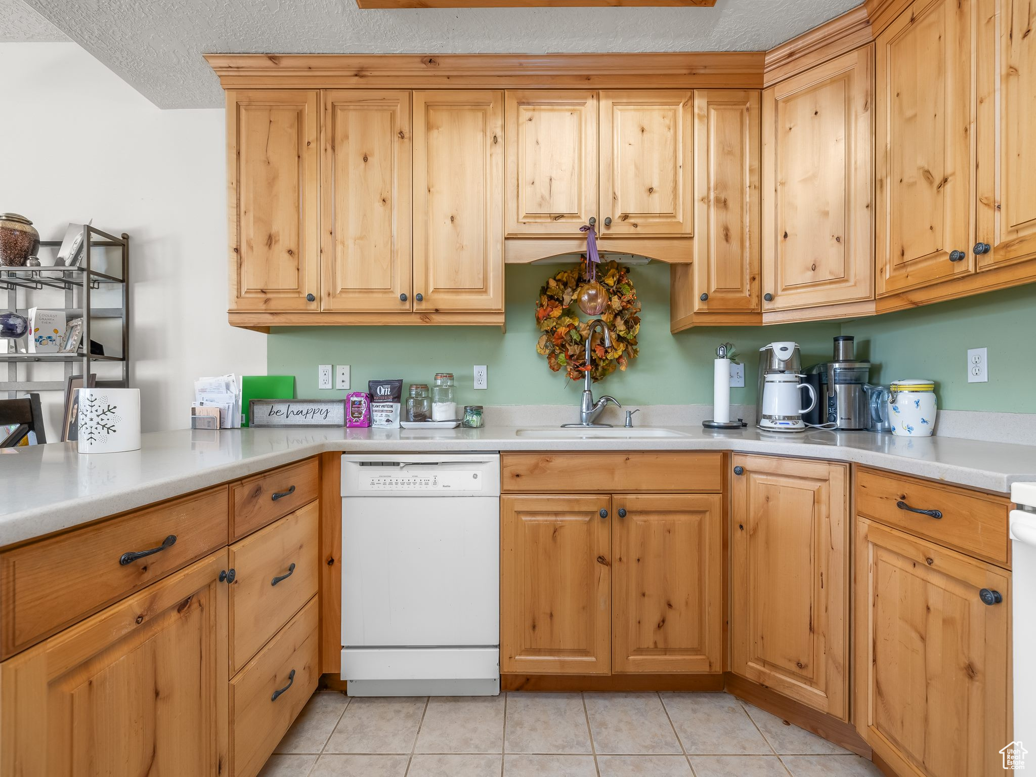 Kitchen featuring sink, light tile patterned floors, a textured ceiling, and white dishwasher