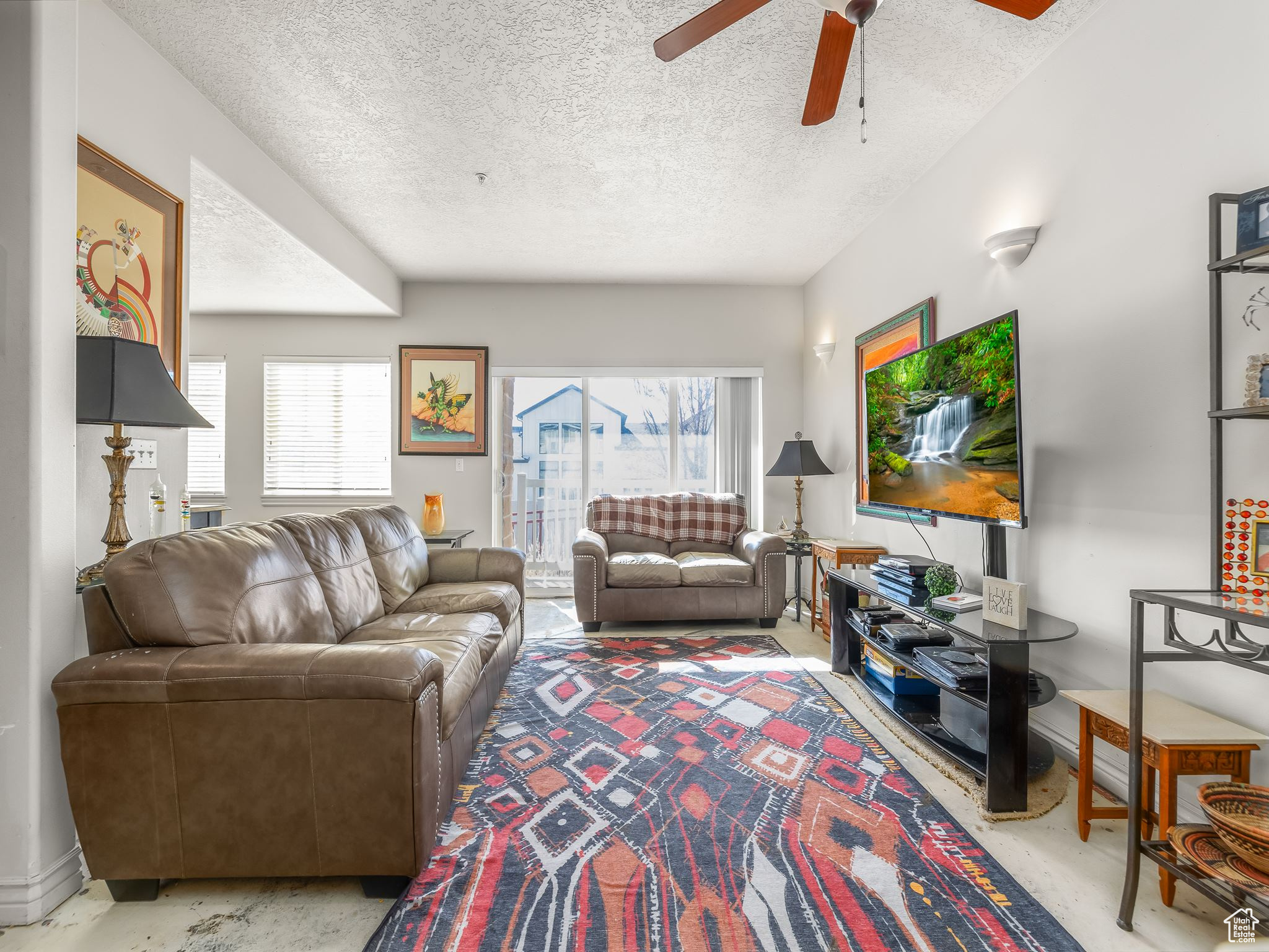 Living room with ceiling fan, a healthy amount of sunlight, and a textured ceiling