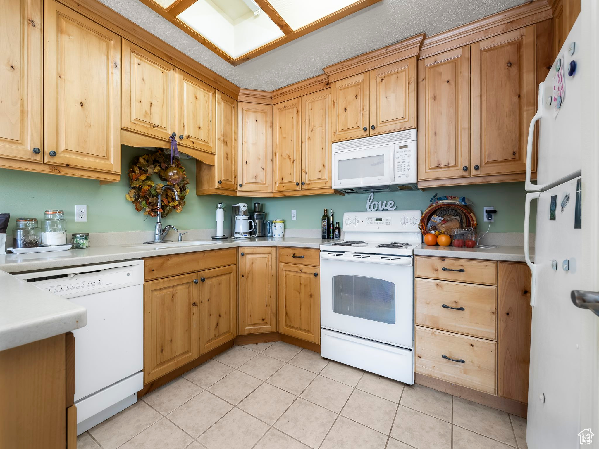 Kitchen with white appliances, sink, and light tile patterned floors
