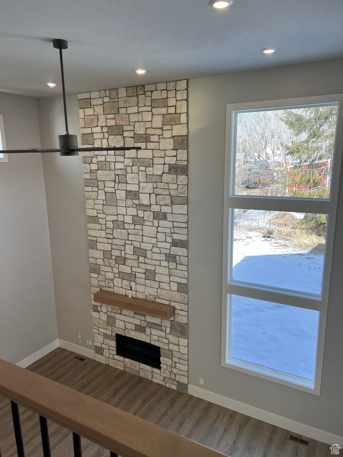 Unfurnished living room with a stone fireplace and hardwood / wood-style floors