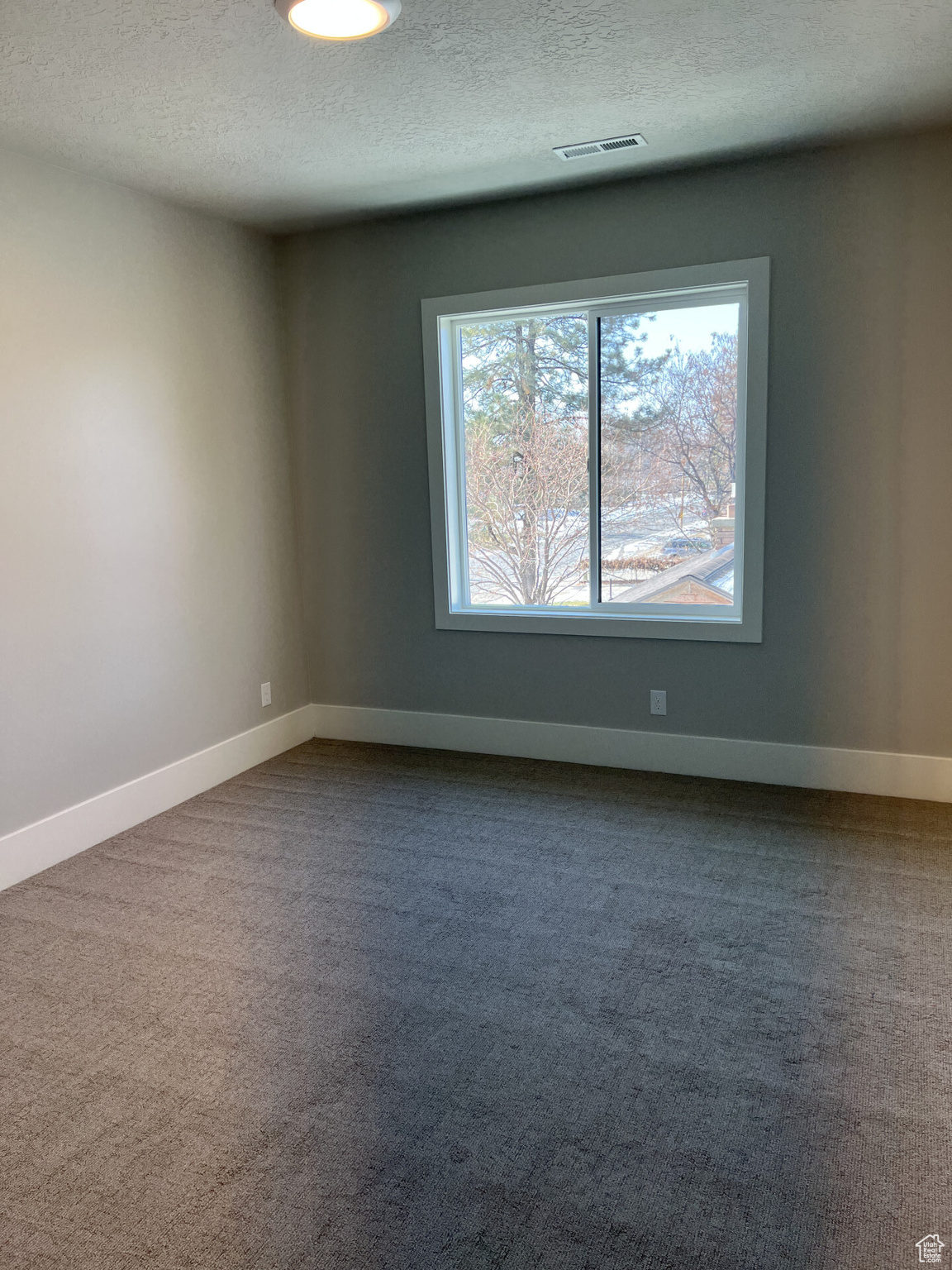 Carpeted empty room featuring a textured ceiling